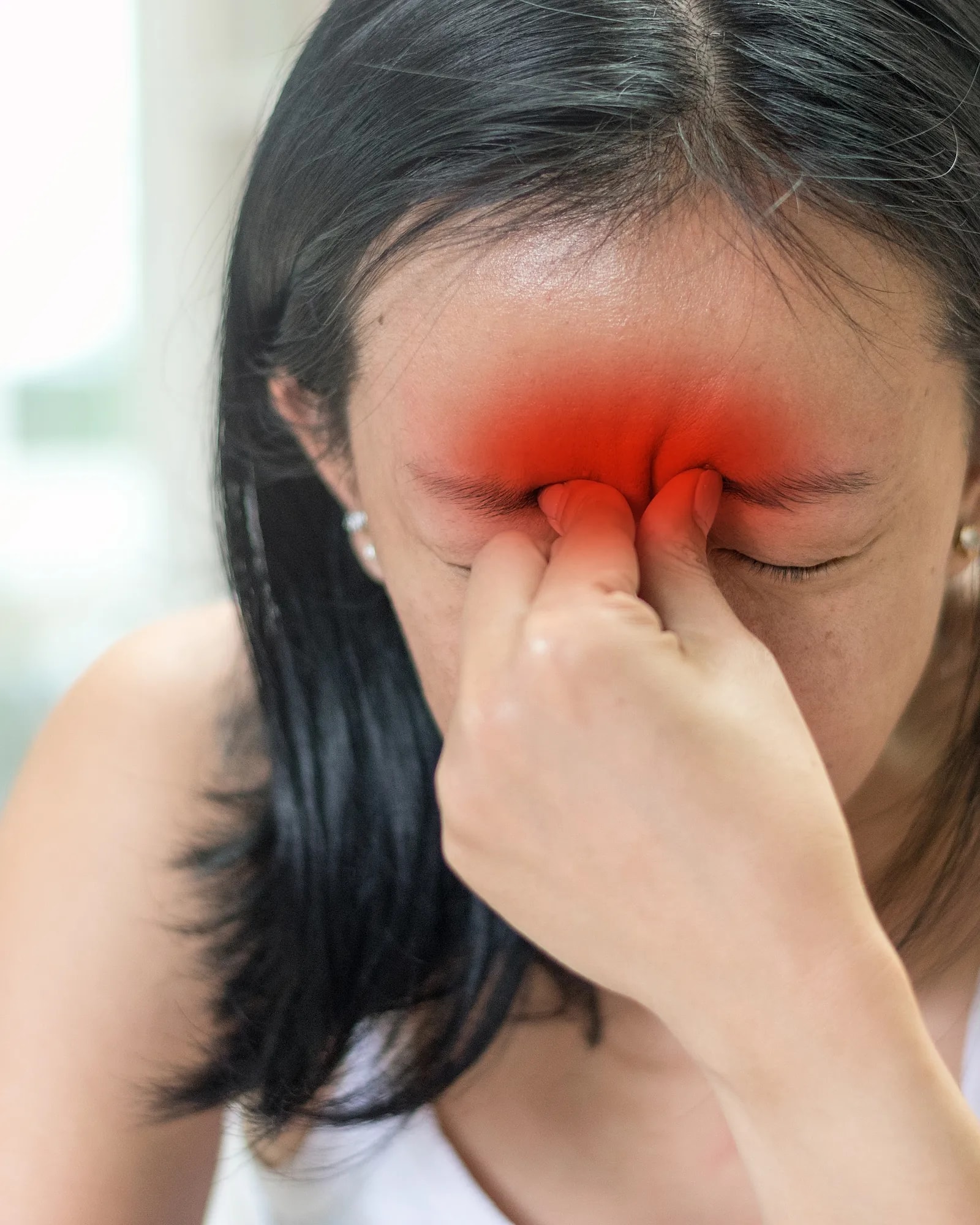 A woman pinching the bridge of her nose with sinus pain